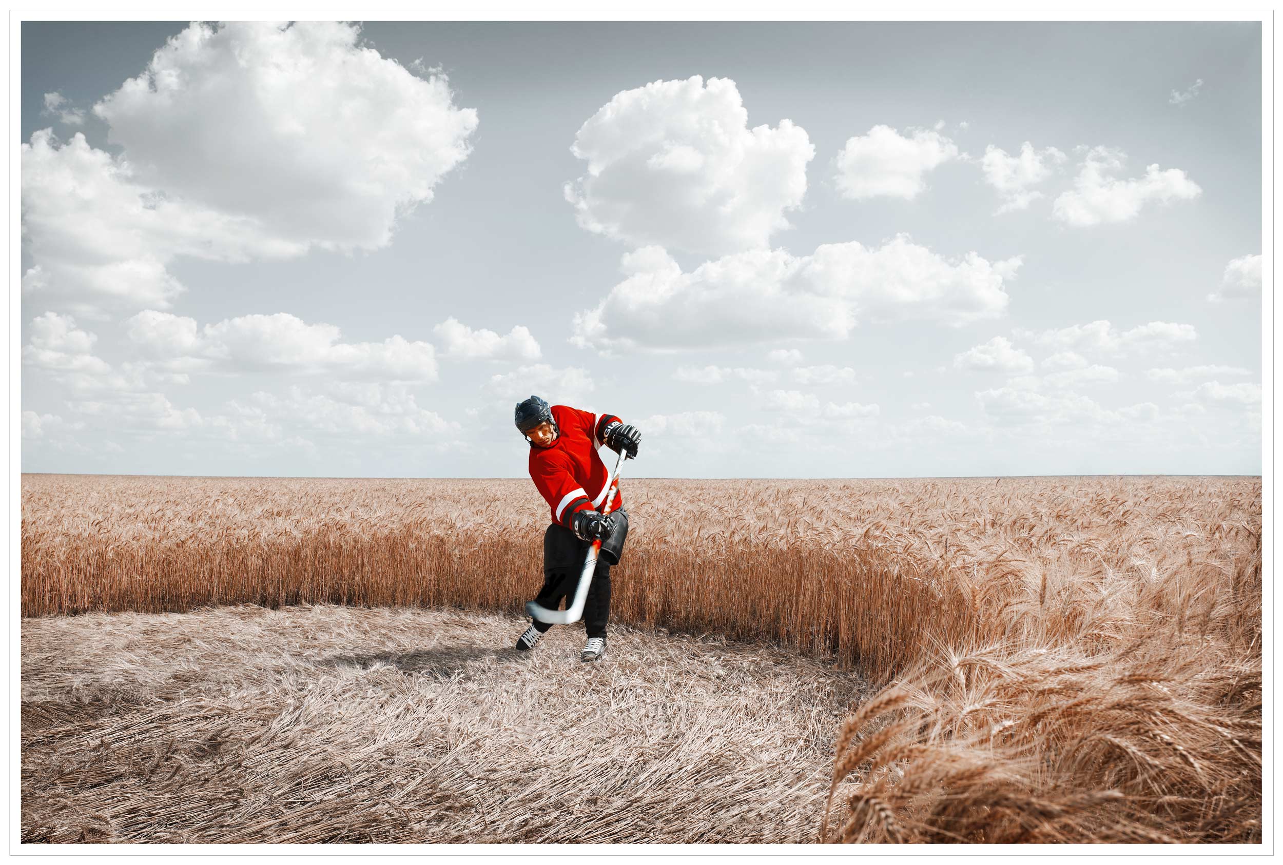Man playing hockey in a wheat field - print campaign for CrossIron Mills